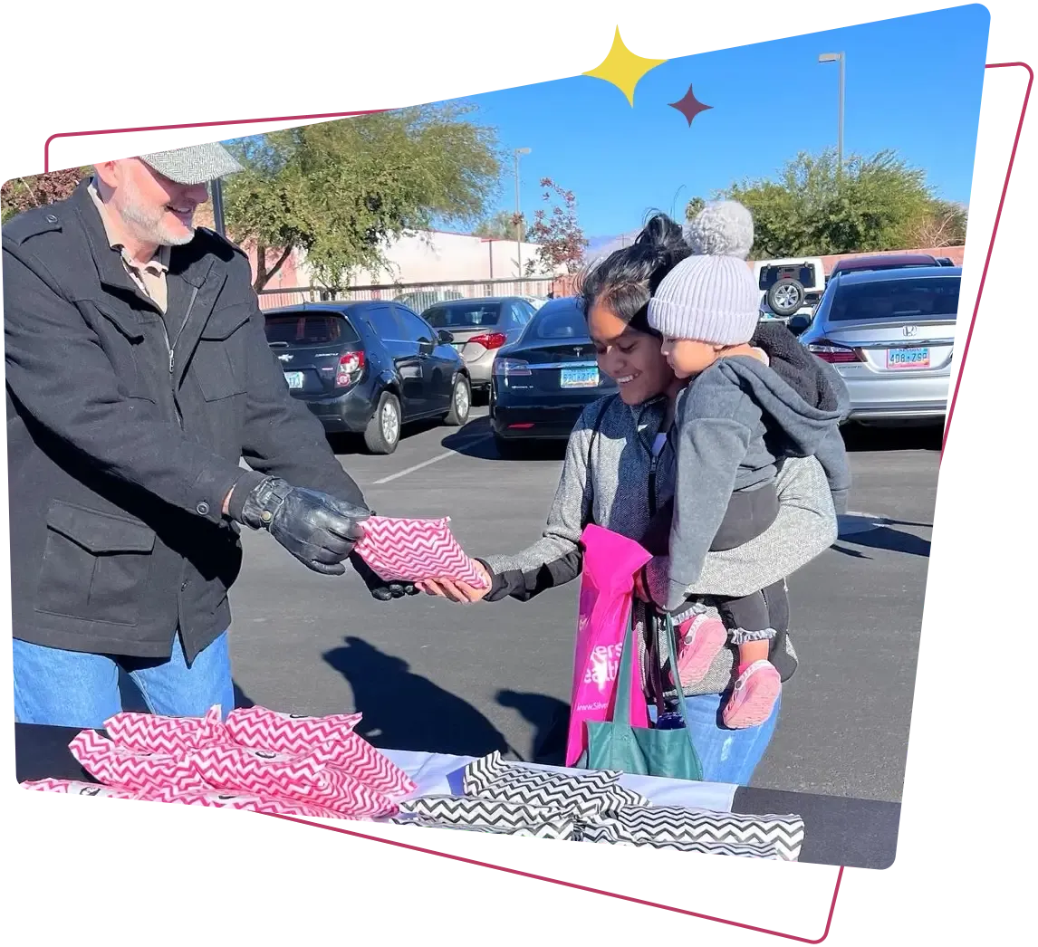 A man hands a woman and her child a Project Marilyn Pink Kit