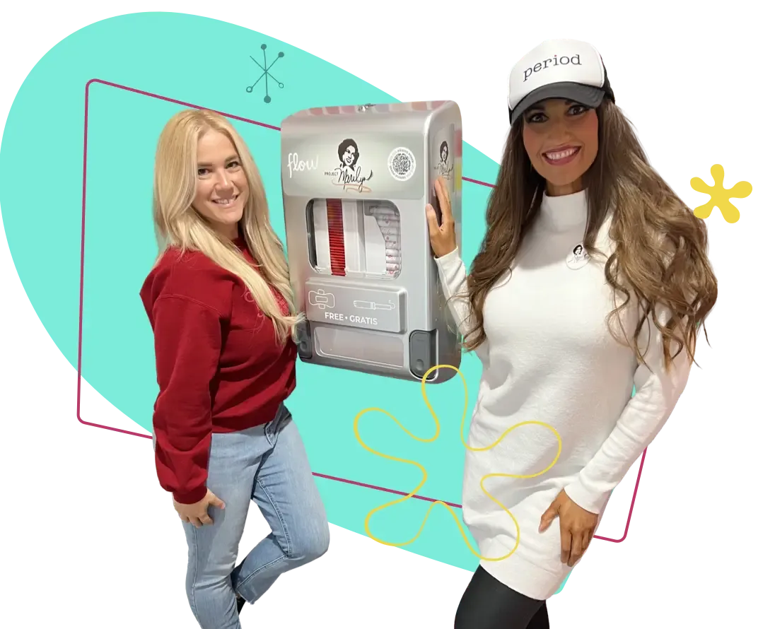 Founder Wendi and Jennifer stand next to a recently installed free period supply dispenser